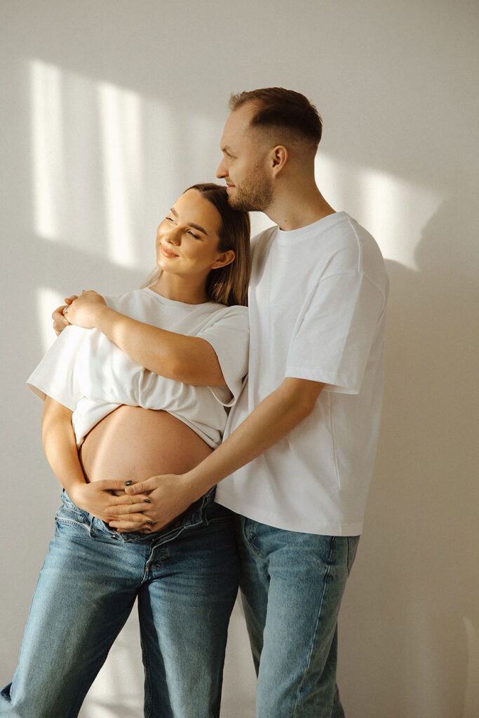 saulėtoje fotostudijoje besilauianti pora su džinsais